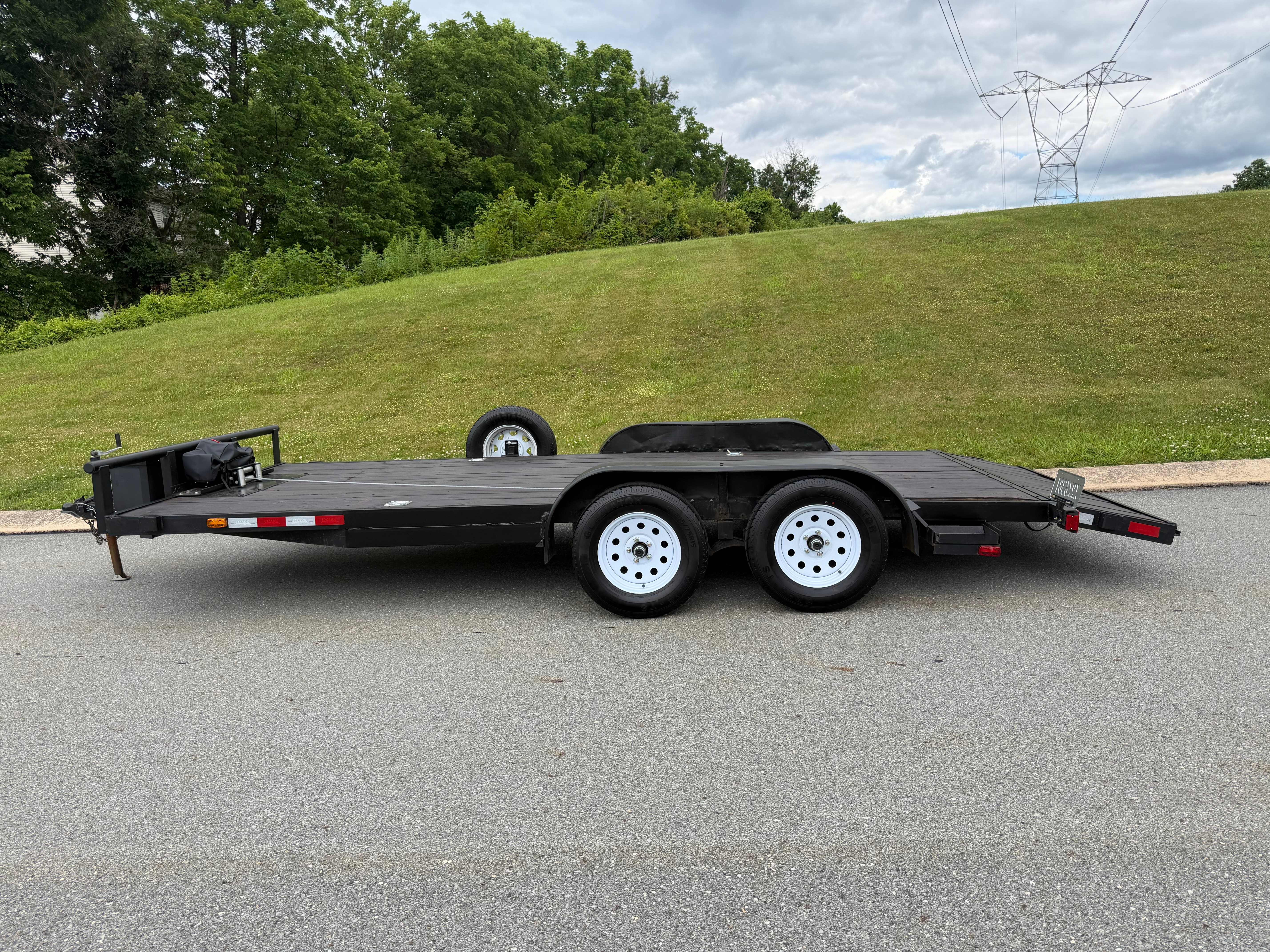 Driver-side profile of black tandem-axle utility car hauler trailer with white wheels in York, PA